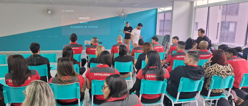 Equipe da BORA! unida para treinamento de atendimento ao cliente, sentados em cadeiras de frente para o projetor.